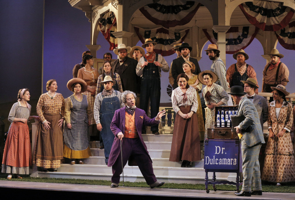 Dulcamara (Patrick Carfizzi) sells his wares, as the Chorus looks on.